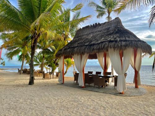 a table and chairs on a beach with palm trees at Coco Grove Beach Resort, Siquijor Island in Siquijor