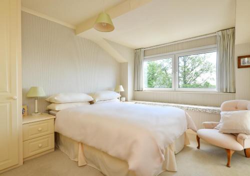 Un dormitorio blanco con una cama grande y una ventana en Gerddi, en Llanbedrog