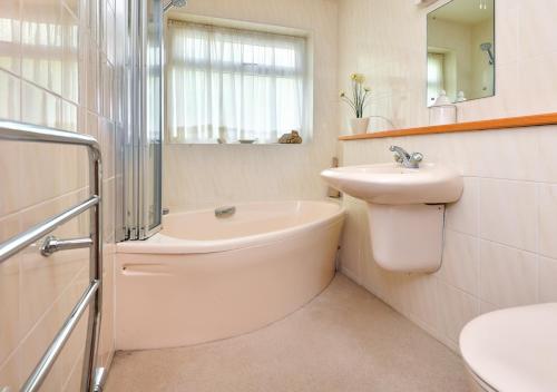 uma casa de banho com uma banheira, um lavatório e um WC. em Gerddi em Llanbedrog