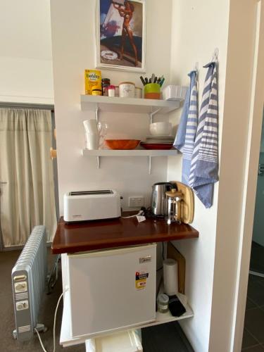 a small kitchen with a counter and a refrigerator at Serenity Lodge for Couples in Ulladulla