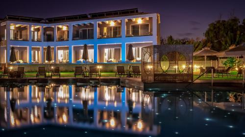 a building with chairs and a pool at night at Acharavi Beach Hotel in Acharavi