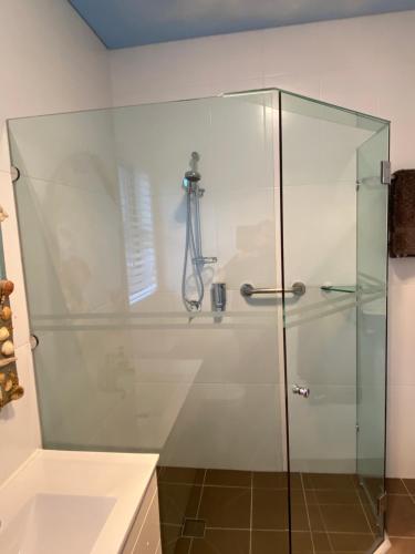 a shower with a glass door in a bathroom at Serenity Lodge for Couples in Ulladulla