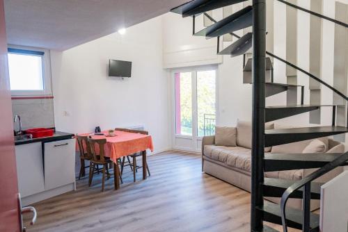 a kitchen and a living room with a table and a spiral staircase at ULVF La petite pierre in La Petite-Pierre