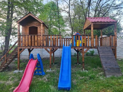 un parque infantil de madera con toboganes y una casa de juegos en Cabanuțele din Lemn en Chişcău