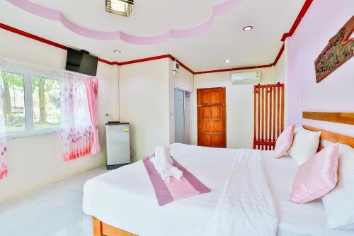 a bedroom with a white bed with pink accents at Ingthara Resort in Phangnga