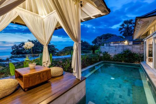 a pool with a table and chairs next to a house at The Chand's Boutique Villa Batu Belig in Seminyak