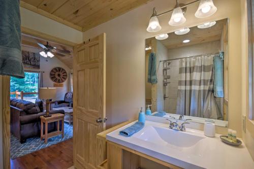 La salle de bains est pourvue d'un lavabo et d'un grand miroir. dans l'établissement Charming Riverfront Cabin with Private Deck and Hot Tub, à Bryson City