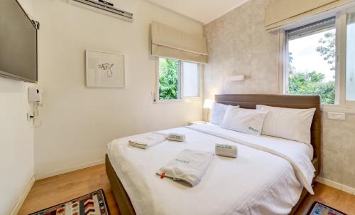 1 dormitorio con 1 cama blanca grande y 2 toallas en SOKOLOV Vacation Boutique Apartments by the sea in nahariya, en Nahariyya