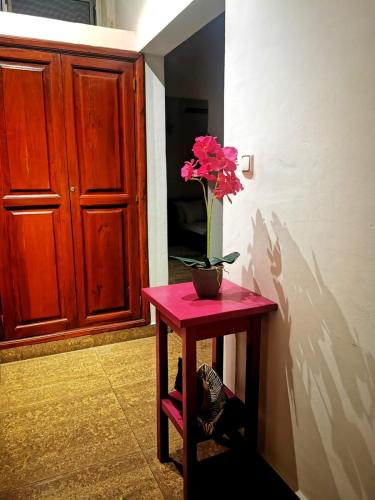 a pink table with a vase with a flower on it at L'Address in Cotonou