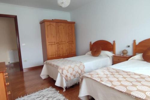 1 dormitorio con 2 camas y armario de madera en Casa da Buxeira . Entorno magico., 