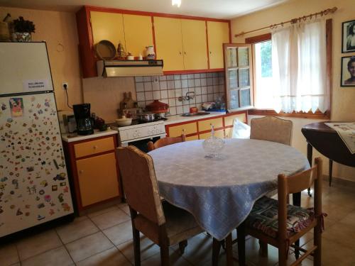 A cosy 60 Sq. m. entire villa في Pendéli: مطبخ مع طاولة مع كراسي وثلاجة