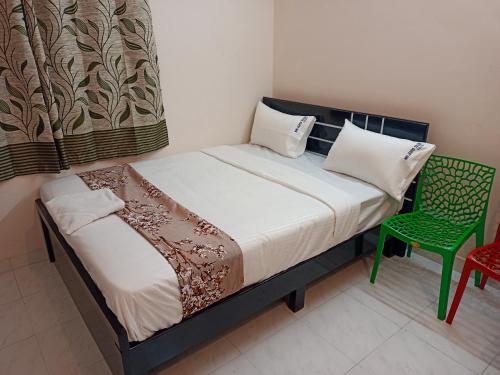 a small bedroom with a bed and a green chair at Royal Guest Inn HSR Layout in Bengaluru