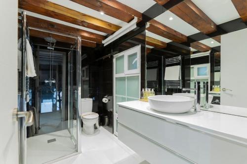 bagno con lavandino, servizi igienici e specchi. di AmazINN Places Gran Via Loft a Madrid