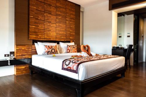 a bedroom with a large bed with a wooden headboard at Am Samui Palace in Lamai
