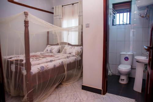 a bedroom with a canopy bed and a toilet at Yobo's Complex Guest House in Kampala