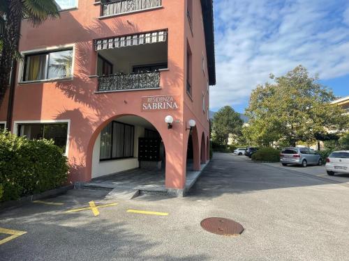 a red building with an archway next to a parking lot at Ascona: Sabrina Apt.238 in Ascona