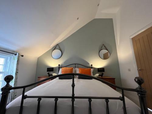 a bedroom with a bed with two mirrors on the wall at Lime Tree Cottage in Tillingham