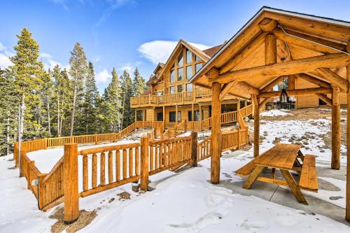 a log home in the snow with a wooden fence at Expansive Alma Cabin with Hot Tub and Mountain Views! in Alma