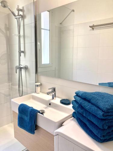 La salle de bains est pourvue d'un lavabo, d'un miroir et de serviettes bleues. dans l'établissement Maison otto, à Menton