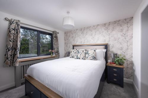 a bedroom with a large bed and a window at Maple Lodge, 20 Roadford Lake Lodges in Lifton