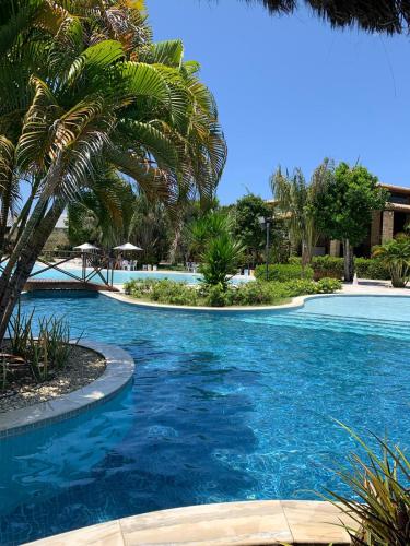 una piscina con palmeras y agua azul en Suíte com varanda no iloa - sem enxoval en Barra de São Miguel
