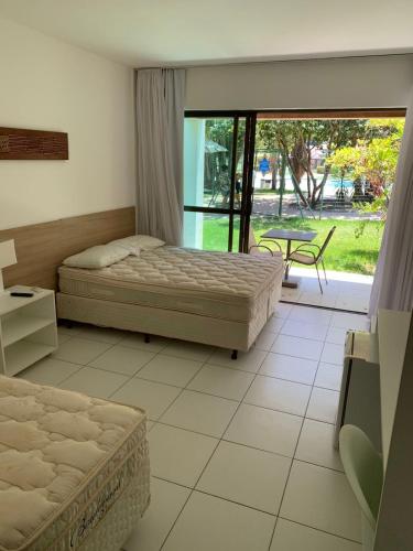 a bedroom with two beds and a sliding glass door at Suíte com varanda no iloa - sem enxoval in Barra de São Miguel