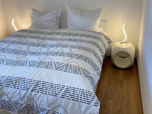 a white bed with white sheets and a white night stand at Ferienwohnung Alte Münz in Müllheim