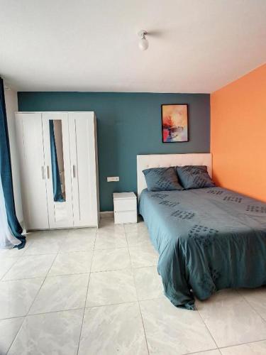 - une chambre avec un lit et un mur orange et bleu dans l'établissement GRAND STUDIO AMIENS GARE TOUT CONFORT WIFI NETFLIX 2PERS, à Amiens