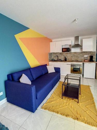 un salon avec un canapé bleu et une cuisine dans l'établissement GRAND STUDIO AMIENS GARE TOUT CONFORT WIFI NETFLIX 2PERS, à Amiens