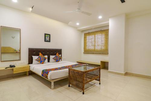 1 dormitorio con cama con espejo y mesa en FabHotel Aamantran & Banquet Halls, en Hyderabad