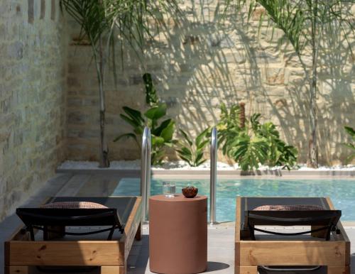 twee stoelen en een tafel naast een zwembad bij Jasmine Villa, with curated design, By ThinkVilla in Perama