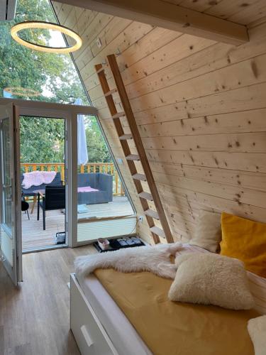 Glamping Holiday House with hot tub and sauna- Hisa oddiha في سمارجيسك توبليس: سرير في غرفة بجدار خشبي