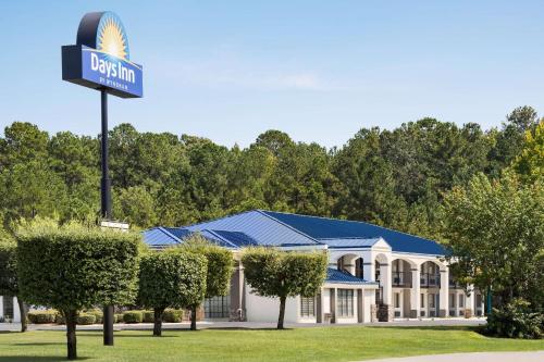 a sign in front of a building with a house at Days Inn by Wyndham Fulton in Fulton