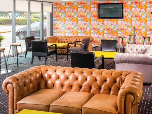 ein Wohnzimmer mit einem Sofa, Tischen und Stühlen in der Unterkunft ibis Styles Barnsley in Barnsley