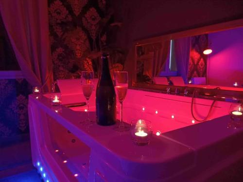 una botella de vino sentada en una mesa con copas de vino en Suite privée avec BALNEO (Jacuzzi ou baignoire)., en Yvetot