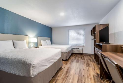 WoodSpring Suites Harrisburg Linglestown في هاريسبورغ: غرفة فندقية بسريرين وتلفزيون بشاشة مسطحة