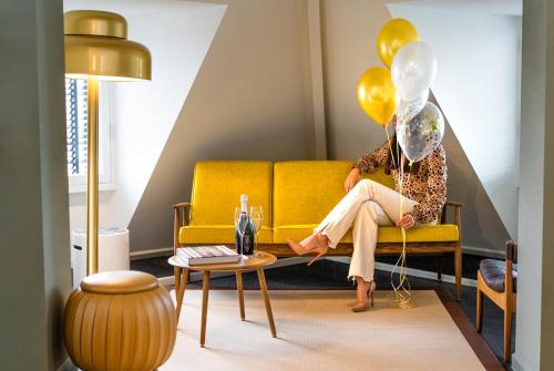 a woman sitting on a yellow couch with balloons at The Collector in The Hague