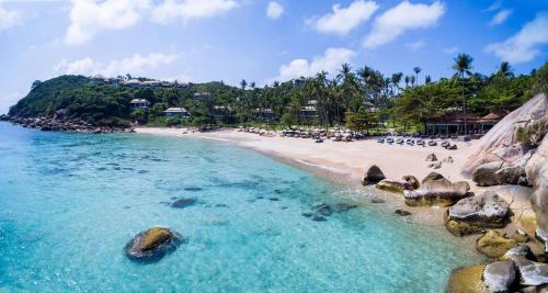a beach with people laying on the sand and the water at Banyan Tree Samui in Lamai