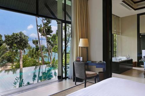 a bedroom with a desk and a view of a pool at Banyan Tree Samui in Lamai