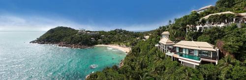 a house on a hill next to the ocean at Banyan Tree Samui in Lamai