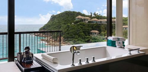 a bathroom with a tub with a view of the ocean at Banyan Tree Samui in Lamai