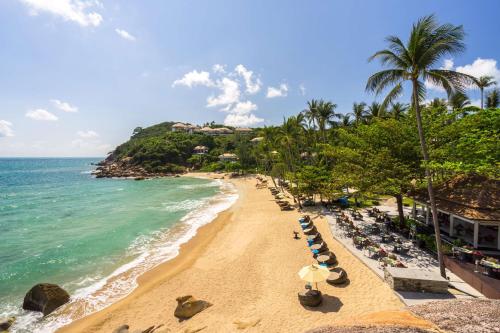 a beach with chairs and umbrellas and the ocean at Banyan Tree Samui in Lamai