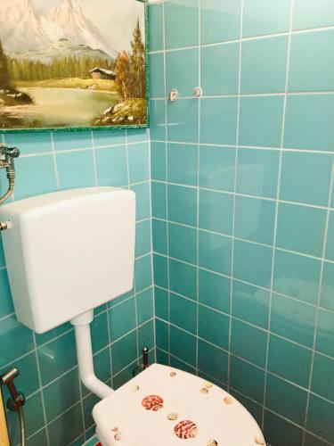 a blue tiled bathroom with a toilet and a painting at Familienapartments mit Balkon oder Terrasse und Garten in Ober-Lembach