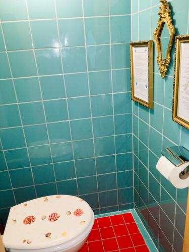 a blue tiled bathroom with a toilet and a red floor at Familienapartments mit Balkon oder Terrasse und Garten in Ober-Lembach