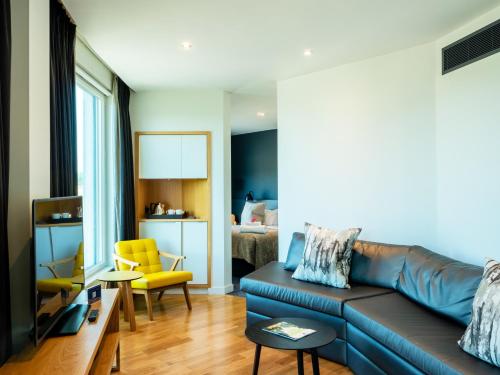 a living room with a blue couch and a yellow chair at Apex City of Bath Hotel in Bath