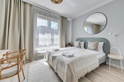 a white bedroom with a large bed and a mirror at Flatbook - City Center Apartments Bastion Wałowa in Gdańsk