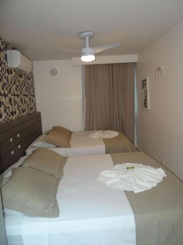 a bedroom with two beds and a ceiling fan at Refúgio em Arraial do Cabo, Momentos inesquecíveis em um apartamento de luxo com 2 quartos, 2 BANHEIROS e 2 vagas de carro entre a praia e a lagoa in Arraial do Cabo