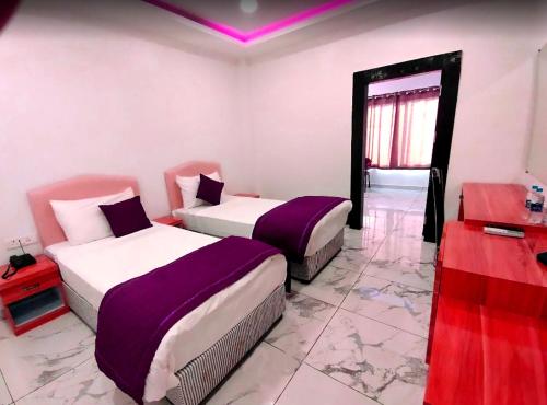 two beds in a room with purple and white at The Buddha Resort in Gaya