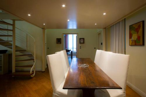 a dining room with a wooden table and white chairs at N 10, Luxury in Turin
