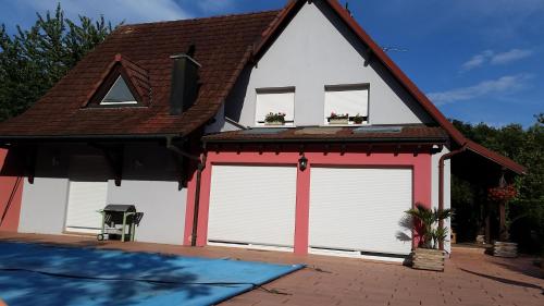 un garage avec deux portes blanches et un toit marron dans l'établissement Chambre des Acacias, à Hirsingue